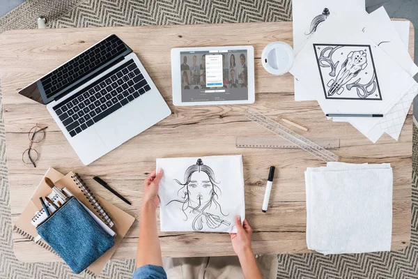 Cropped image of female designer putting painting on table with laptop and digital tablet with linkedin on screen — Stock Photo