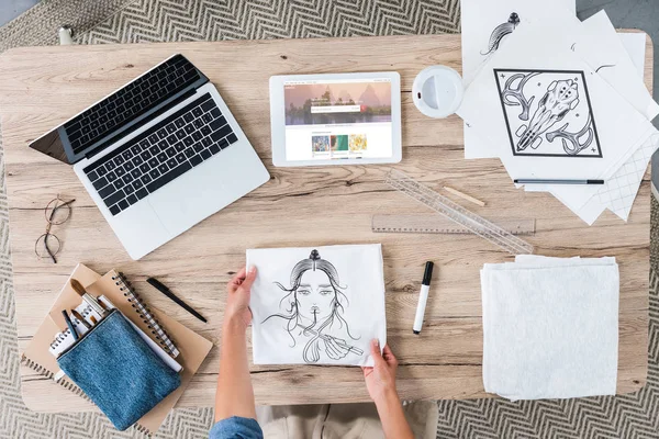 Imagen recortada del diseñador femenino poniendo pintura en la mesa con el ordenador portátil y la tableta digital con shutterstock en la pantalla - foto de stock