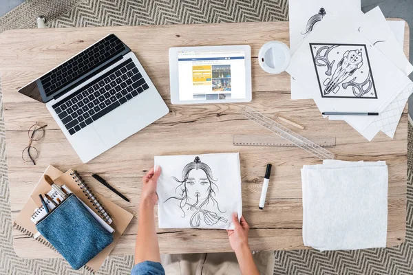 Обрезанный образ женщины-художника положить картину на стол с ноутбуком и цифровой планшет с booking.com на экране — стоковое фото