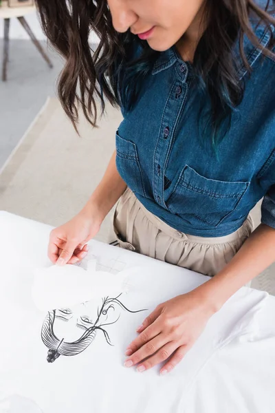 Immagine ritagliata di stilista donna che fa stampa su t-shirt bianca — Foto stock