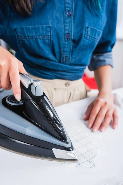 Cropped image of female designer ironing white t-shirt with print — Stock Photo