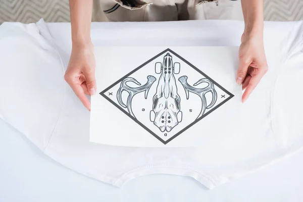 Cropped image of female fashion designer choosing print for empty white t-shirt — Stock Photo