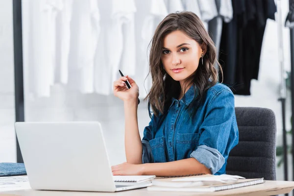 Smiling attractive female designer working at table with laptop — Stock Photo