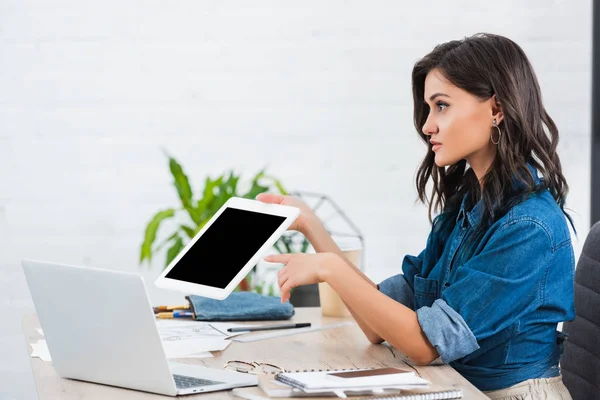 Vue latérale de la jeune femme pointant sur la tablette numérique avec écran blanc à la table — Photo de stock