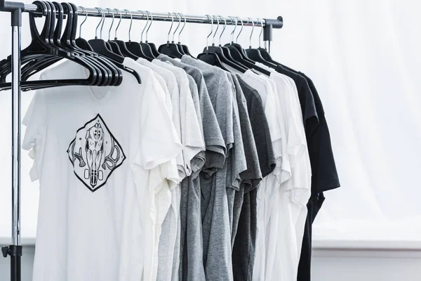 Selective focus of t-shirts with print on hangers in clothing design studio — Stock Photo