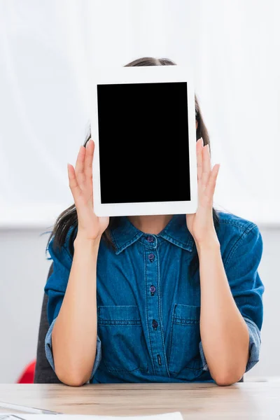 Mujer joven cubriendo cara por tableta digital con pantalla en blanco - foto de stock