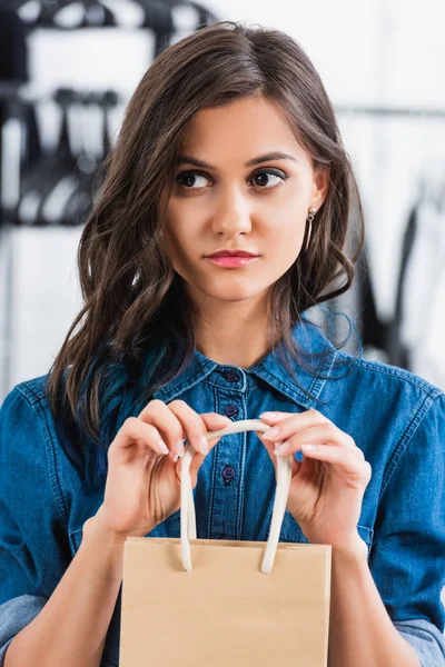 Atractiva bolsa de papel de mujer joven en estudio de diseño de ropa - foto de stock