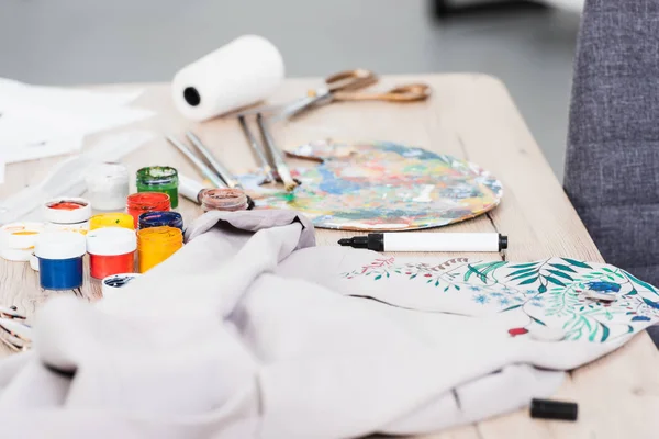 Foyer sélectif de peintures colorées et veste de peinture à la table dans le studio de conception de vêtements — Photo de stock