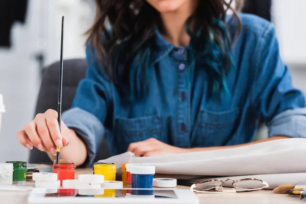 Cropped image of female fashion designer painting on jacket at working table in clothing design studio — Stock Photo