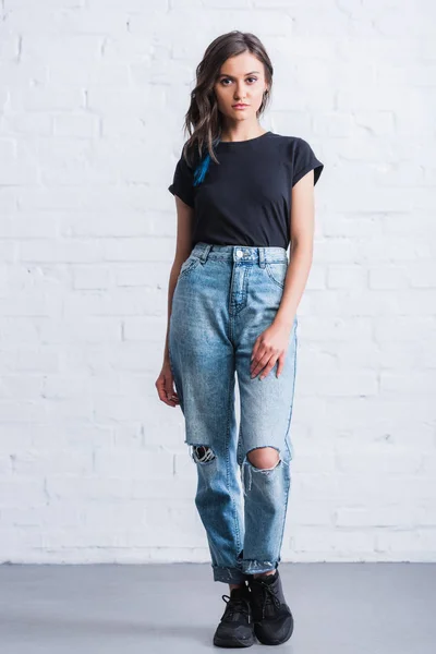 Attractive young woman in empty black t-shirt in front of brick wall — Stock Photo