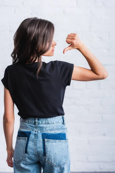 Selective focus of young woman pointing by finger on back of empty black t-shirt — Stock Photo