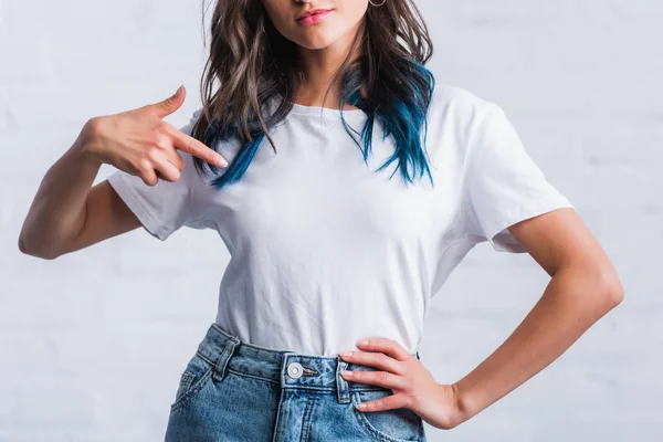Imagen recortada de mujer joven señalando con el dedo en la camiseta blanca vacía - foto de stock
