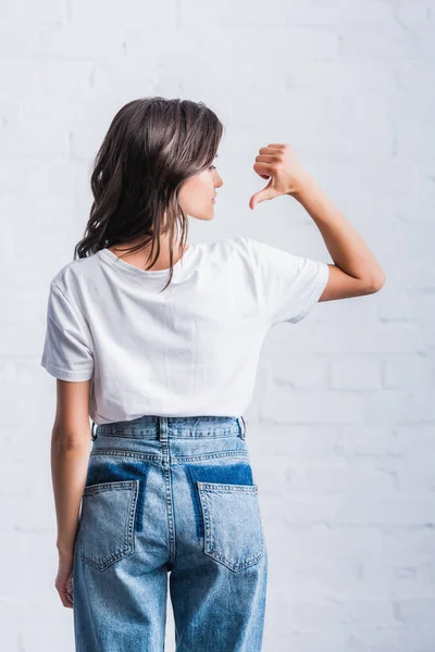 Selective focus of young woman pointing by finger on back of empty white t-shirt — Stock Photo