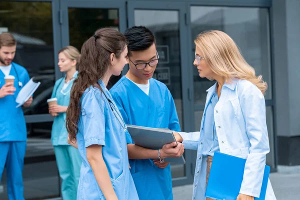 Teacher and multicultural students looking at folder at medical university — Stock Photo