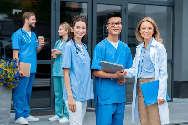 Lächelnder Lehrer und multikulturelle Studenten vor der Kamera der Medizinischen Universität — Stockfoto
