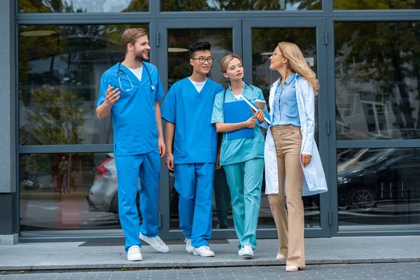 Professor andando e conversando com estudantes multiculturais na universidade de medicina — Fotografia de Stock
