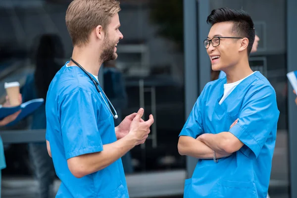 Estudantes multiculturais falando e rindo perto da universidade médica — Fotografia de Stock