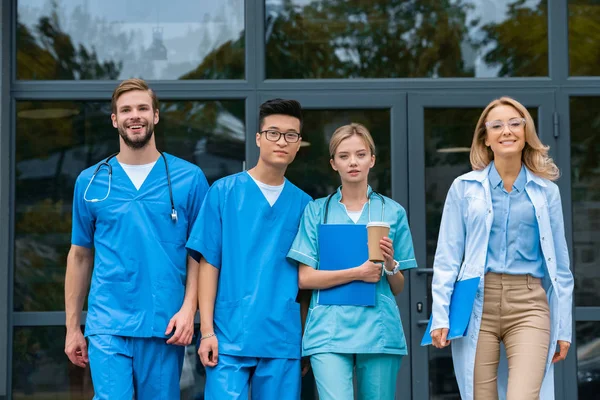 Professeur souriant avec des étudiants multiculturels à pied de l'université de médecine — Photo de stock