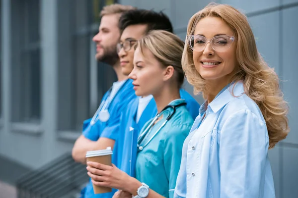 Усміхнений вчитель з мультикультурними студентами, що стоять в ряд біля медичного університету — стокове фото