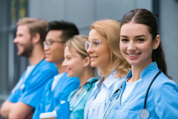 Teacher and happy multicultural students standing in row near medical university — Stock Photo