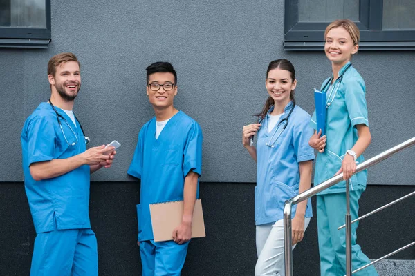 Усміхнені мультикультурні студенти, які дивляться на камеру біля медичного університету — стокове фото