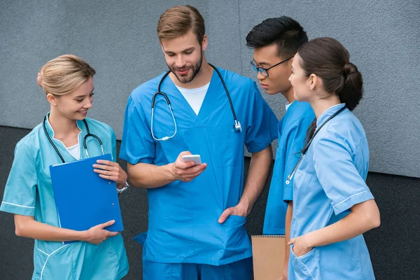 Multikulturelle Medizinstudenten schauen an der Medizinischen Universität aufs Smartphone — Stockfoto