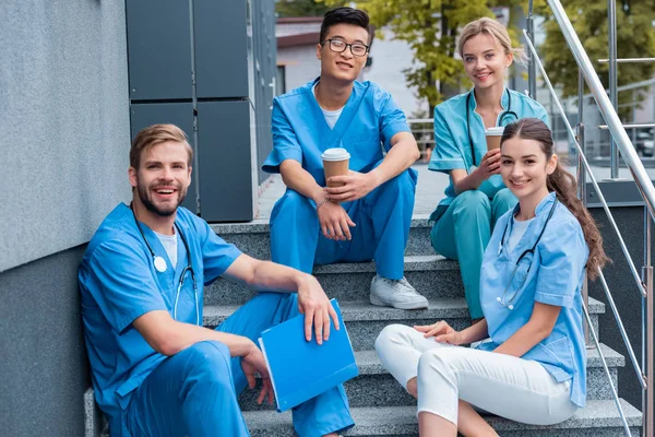 Felici studenti di medicina multiculturale seduti sulle scale e guardando la fotocamera — Foto stock