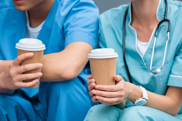 Image recadrée des étudiants en médecine tenant des tasses à café jetables — Photo de stock