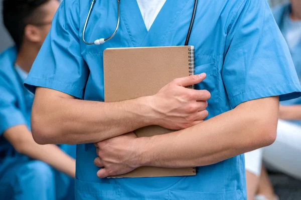 Abgeschnittenes Bild eines Medizinstudenten, der mit Notizbuch steht — Stockfoto