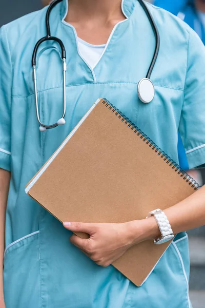 Abgeschnittenes Bild eines Medizinstudenten, der mit Notizbuch steht — Stockfoto