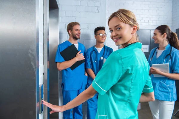 Estudante de medicina atraente pressionando botão elevador na universidade médica — Fotografia de Stock