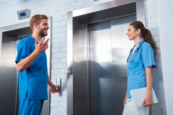 Medical students talking while waiting elevator in university — Stock Photo