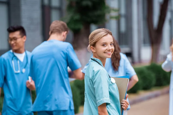 Studente di medicina sorridente guardando la fotocamera sulla strada vicino all'università medica — Foto stock