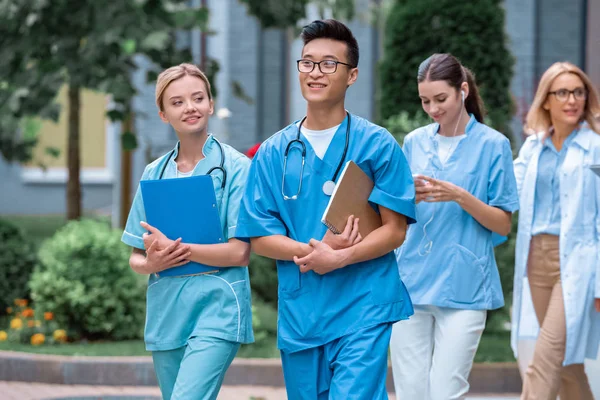 Studenti multiculturali e insegnanti che camminano per strada vicino all'università medica — Foto stock