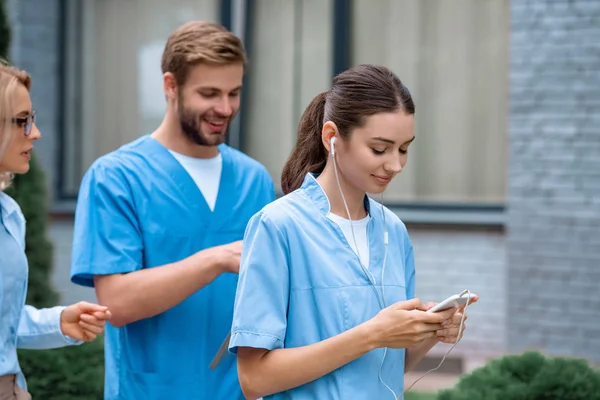 Studente di medicina che cammina per strada e ascolta musica con smartphone — Foto stock