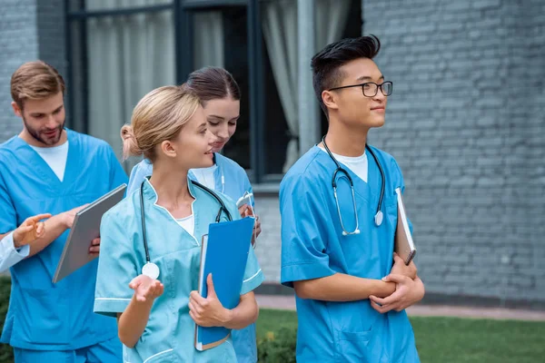 Studenti multiculturali che parlano mentre camminano per strada vicino all'università medica — Foto stock