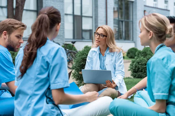 Teacher having lesson with students at medical university on green grass — Stock Photo