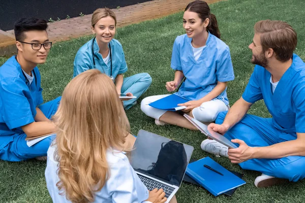 Teacher having lesson with happy multicultural students at medical university on green grass — Stock Photo