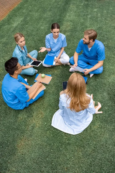 Vista ad alto angolo di insegnante che ha lezione con studenti multietnici presso l'università medica su erba verde — Foto stock