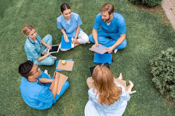 Vista ad alto angolo di insegnante che ha lezione con gli studenti multiculturali presso l'università medica su erba verde — Foto stock