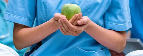 Abgeschnittenes Bild eines Medizinstudenten, der einen reifen grünen Apfel in den Händen hält — Stockfoto