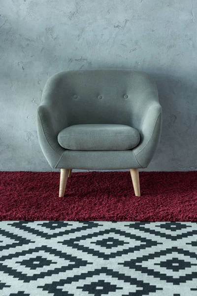 Grey armchair on burgundy carpet near grey wall in office — Stock Photo