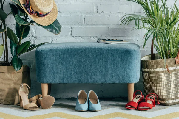 Différentes chaussures sous la chaise dans le couloir à la maison — Photo de stock