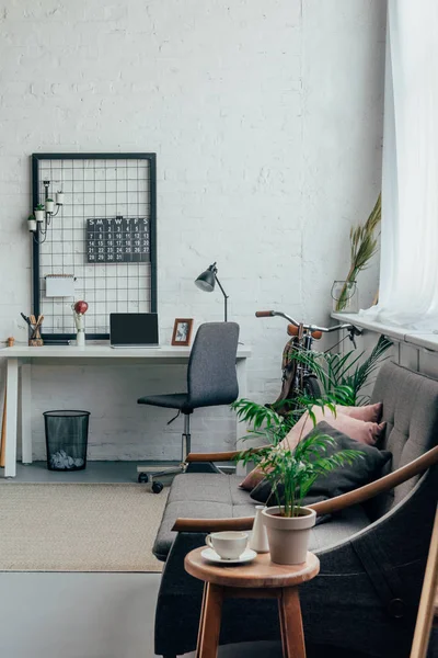 Laptop mit leerem Bildschirm auf Tisch, Sofa und Tasse Kaffee im modernen Wohnzimmer — Stockfoto