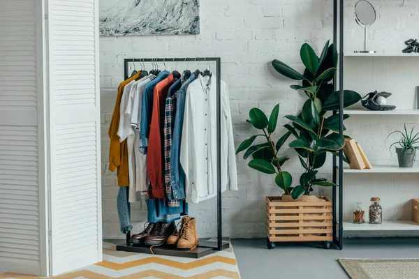 Verschiedene Hemden auf Kleiderbügeln, Schuhe im Regal im Wohnzimmer — Stockfoto