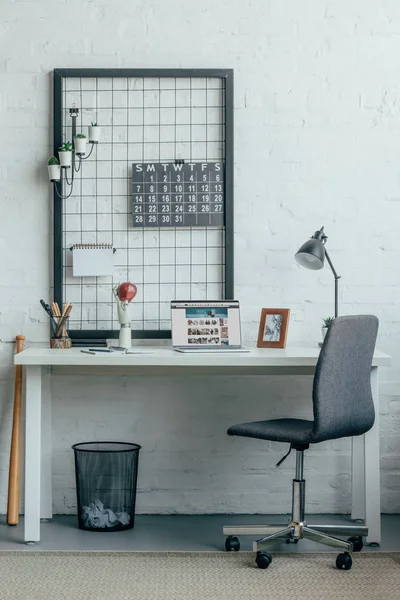 Portátil con página amazónica cargada en la mesa en la oficina moderna - foto de stock