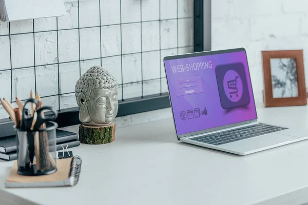 Laptop with loaded web shopping page on table in modern office — Stock Photo