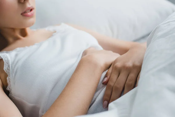 Cropped shot of young woman suffering from stomach pain in bed — Stock Photo