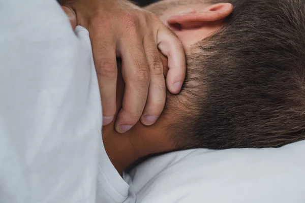 Vista de cerca del hombre que sufre de dolor en el cuello mientras está acostado en la cama - foto de stock