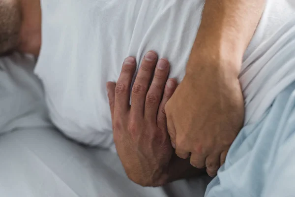 Close-up partial view of man suffering from stomach pain in bed — Stock Photo